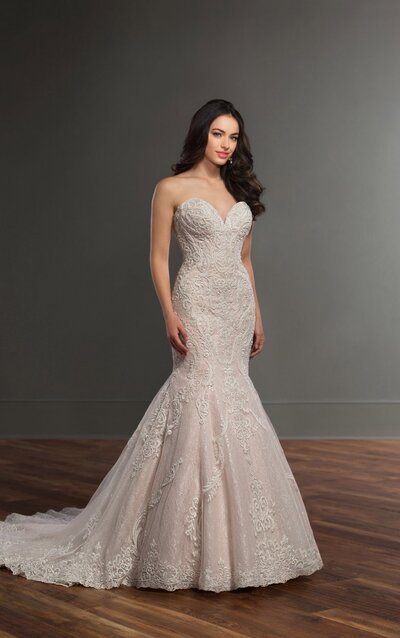 ORNATELY BEADED WEDDING DRESS WITH LONG LACE TRAIN Giving a sophisticated update to a classic silhouette, brides will instantly fall in love with this ornately beaded wedding dress with long lace train from Martina Liana. From the plunging, sweetheart neckline through the bodice of this dropped-waist gown, lace patterns create shapes and are adorned with a delicate, silver finish truly making the pattern stand out. In a flattering trumpet silhouette, this lace, tulle and Royal organza over matte-side lustre satin gown includes a layer of sequin tulle in its full skirt, adding a subtle shimmer to this stunning gown. Sheer cutouts adorn each side of this strapless style, and extend to the back of the gown, creating a corset-inspired look. The back of this gown features a lace-detailed train and zips up beneath crystal buttons.