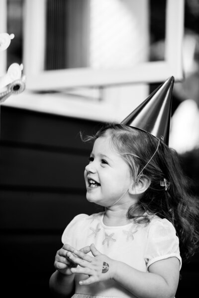 a little girl wearing a party hat smiles
