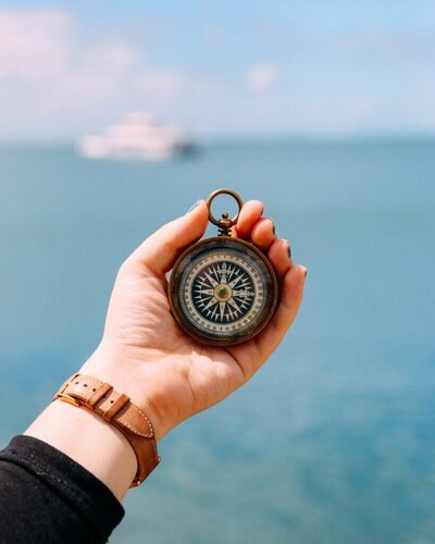 Women holding compass with sea background