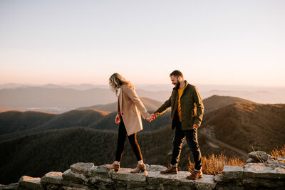 man and woman walking and holding hands with mountains in background