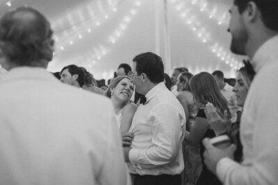 a bride and group have a smitten moment on the dance floor of their tented wedding reception