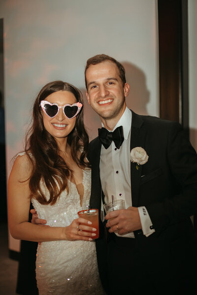 bride in heart sunglasses poses with groom