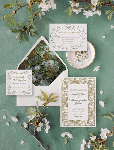 Antique botanical wedding invitations ona green background with white florals
