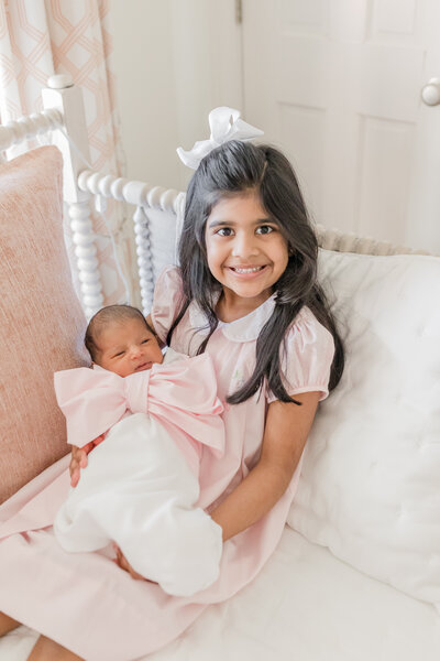 Young girl holding newborn sister. -Newborn Photography Greenville SC