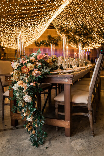 Stunning floral cascades line tables of this fall reception with terra cotta, blush, yellow hues, and taupe taper candles. Florals featuring dahlias, roses, and rain tree pods create lush arrangements. Designed by Rosemary and Finch in Nashville, TN.