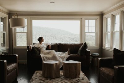 Bride sitting on couch and looking out window, Berkshire Farm Wedding