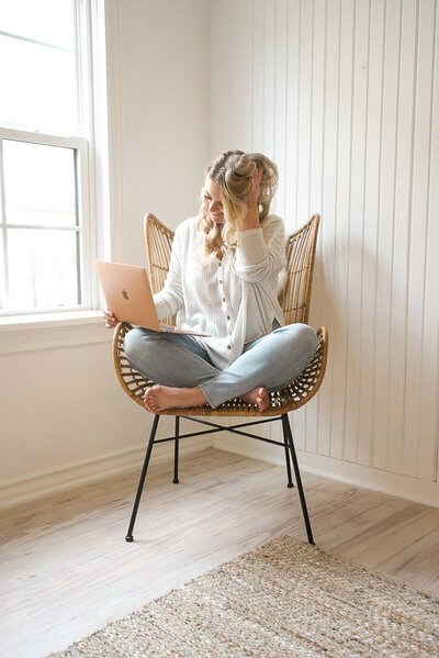 Mollie Mason sitting in a chair with her legs crossed holding her laptop on her lap