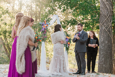 A happy couple exchanging vows at the River Landing during the fall time at sunset by JoLynn Photography, a Wilmington wedding photographer