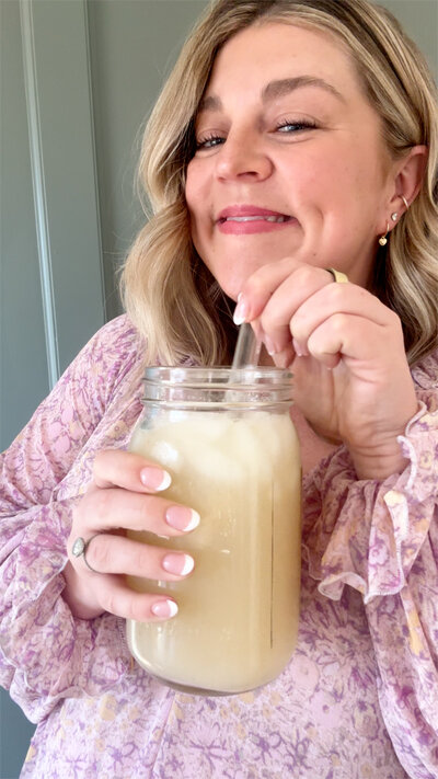 Mollie Mason smiling and holding a drink in a clear mason jar with a straw