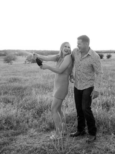 Couple laughs at each other, popping champagne at their family ranch.