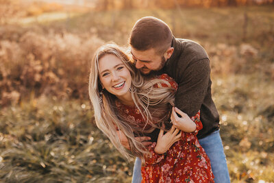 Golden hour engagement photo of man hugging woman from behind