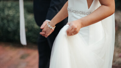 A close up picture of bride and groom walking holding hands. Bride is carrying her dress in the other hand. Photo taken by Orlando Wedding Photographer Four Loves Photo and Film.