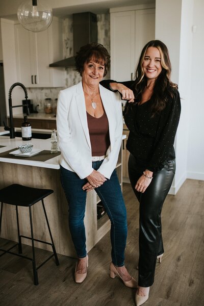 Two female realtors posing in kitchen