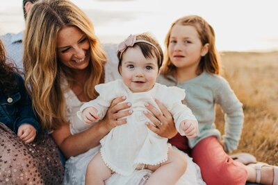 toddler girl smiling with mom and sister