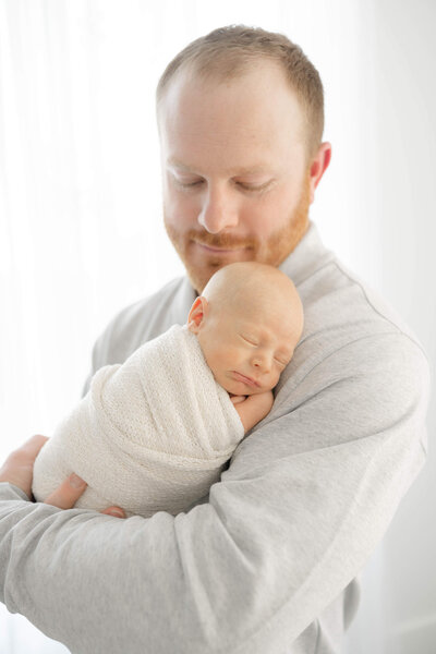 proud father holding his sleeping son in Wheeler District photography studio