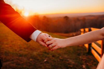 photo of a two hands showing off their rings at sunset