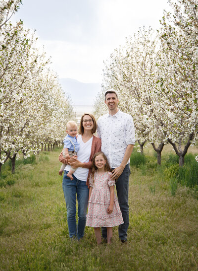 A small family has a family portrait taken in an orchard by Diane Owen Photography.