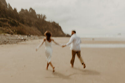 man and woman holding hands running across the beach