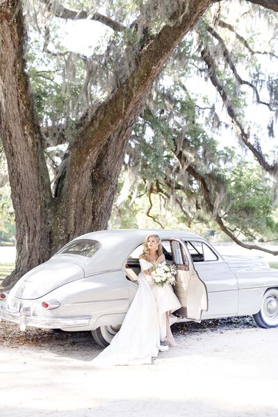 Bride standing next to vintage car at Middleton Plantation