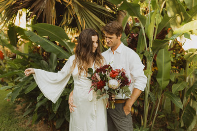 bride and groom standing in front of banana trees