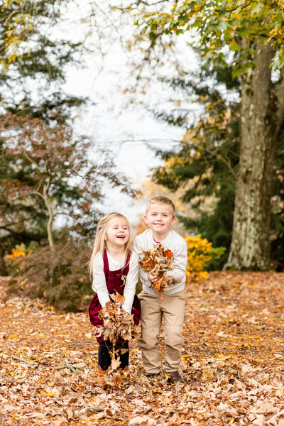 Kids throwing leaves in the air at family Fall session