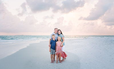 Karen Shanely and family pose on the beach of Anna Maria Island's pastel skies, and soft white sand.