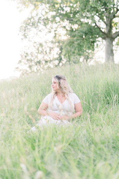 pregnant mom sitting in field in westchester