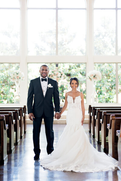 Bride and Groom smiling and holding hands in a chapel