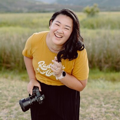 A person laughing and leaning over as they hold a camera