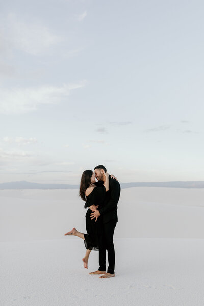 man holding woman on white sand dunes about to kiss in new mexico