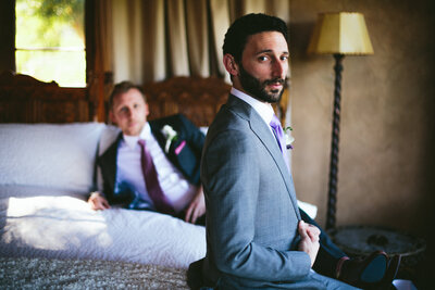 Same sex couple poses for photo in their wedding suits