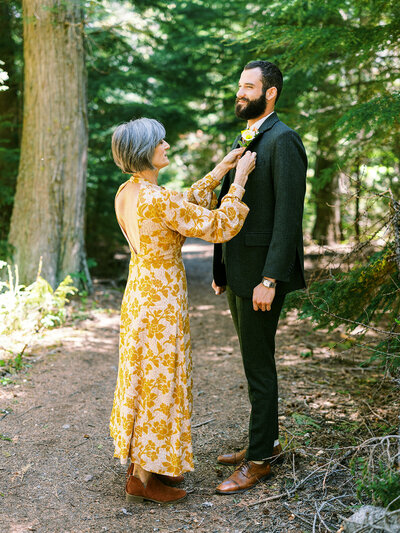 Mother of the bride pinning a boutonniere on the groom before the ceremony at a Glacier National Park wedding.