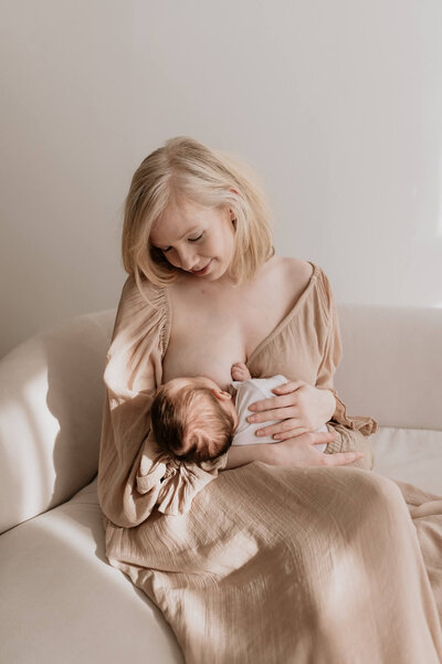 Mama geeft borstvoeding aan pasgeboren baby tijdens newbornshoot