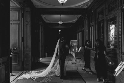 B & W photo of bride and person escorting her about to enter wedding ceremony