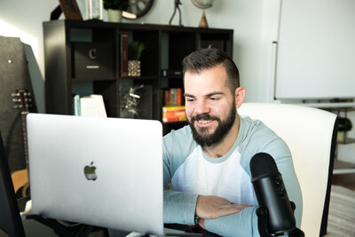 Man sitting at his desk smiling looking at his computer