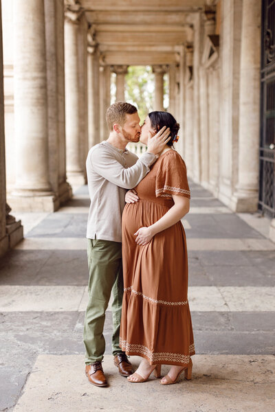 Pregnant woman and her husband sharing a kiss in-between columns of Rome. Taken by Rome Photographer, Tricia Anne Photography.