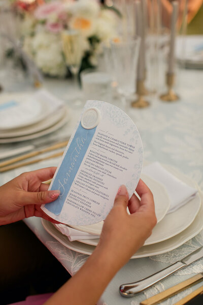 Semi-circle menu card with light blue silk ribbon place card with white calligraphy and wax seal