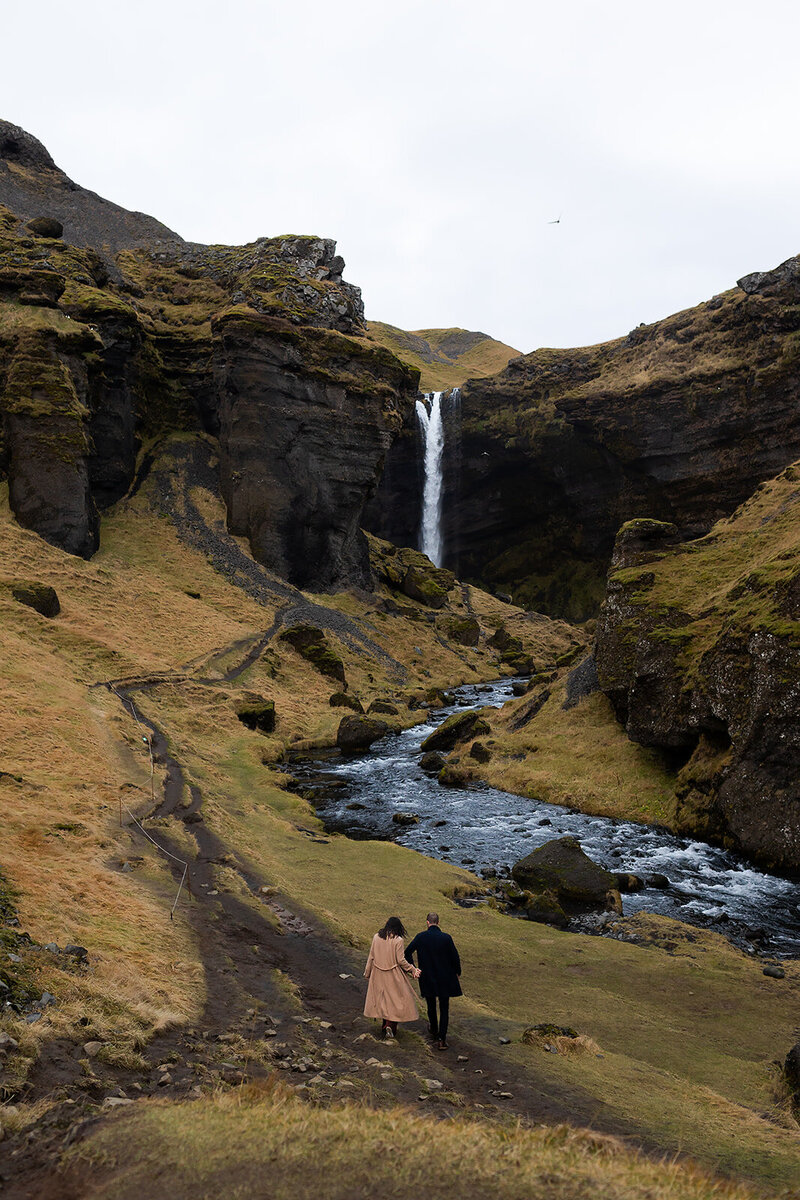 couple looking out at iceland waterfall