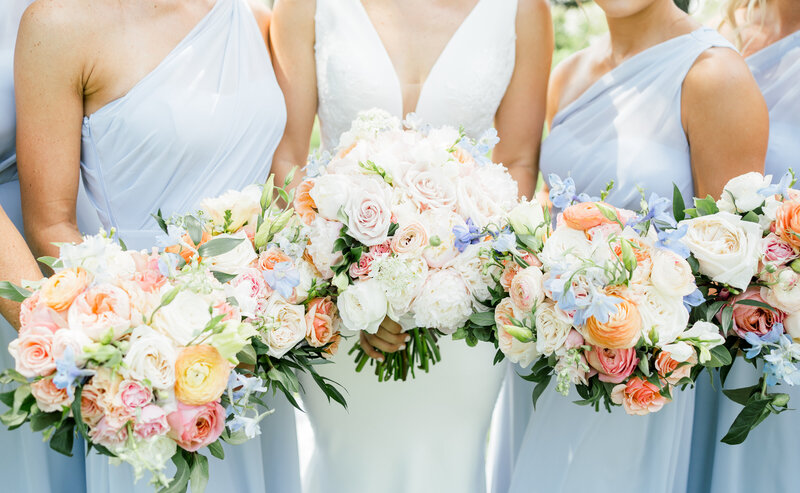 bride standing with bridesmaids holding a flower bouquet