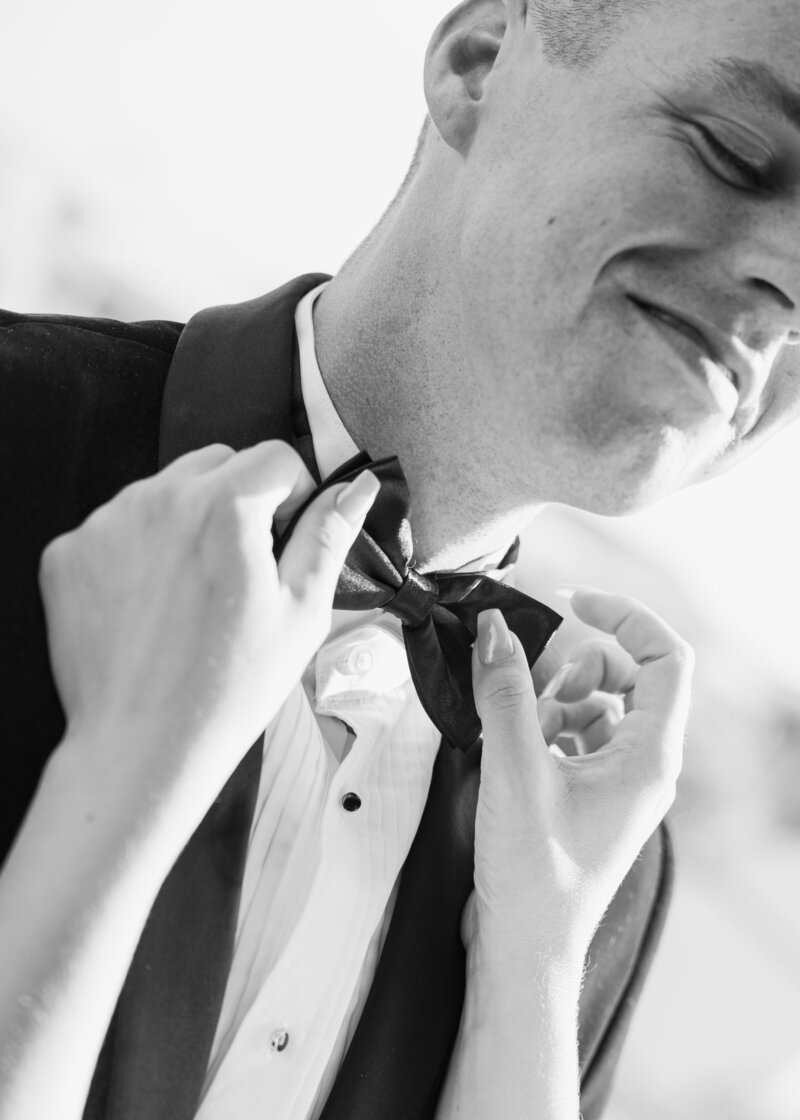 Bride photographed adjusting Grooms bowtie during their wedding in Florida