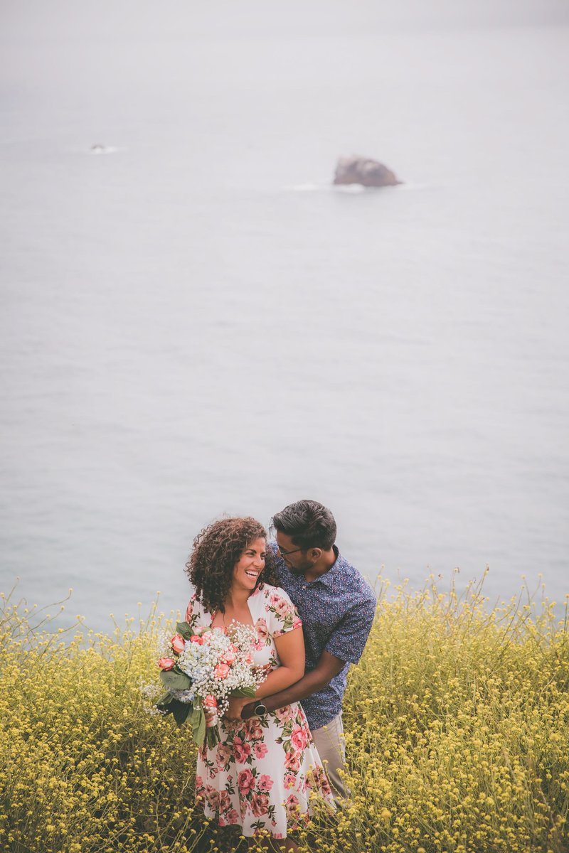 A couple prom poses among yellow wildflowers in Big Sur for their engagement.