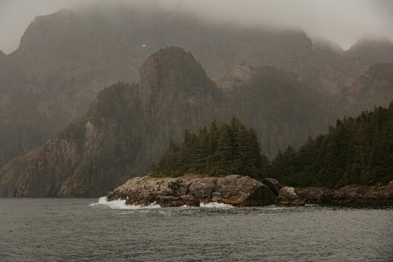 A view of a jutted cliffside is seen out in the waters of Resurrection Bay in Seward, Alaska on a foggy day.