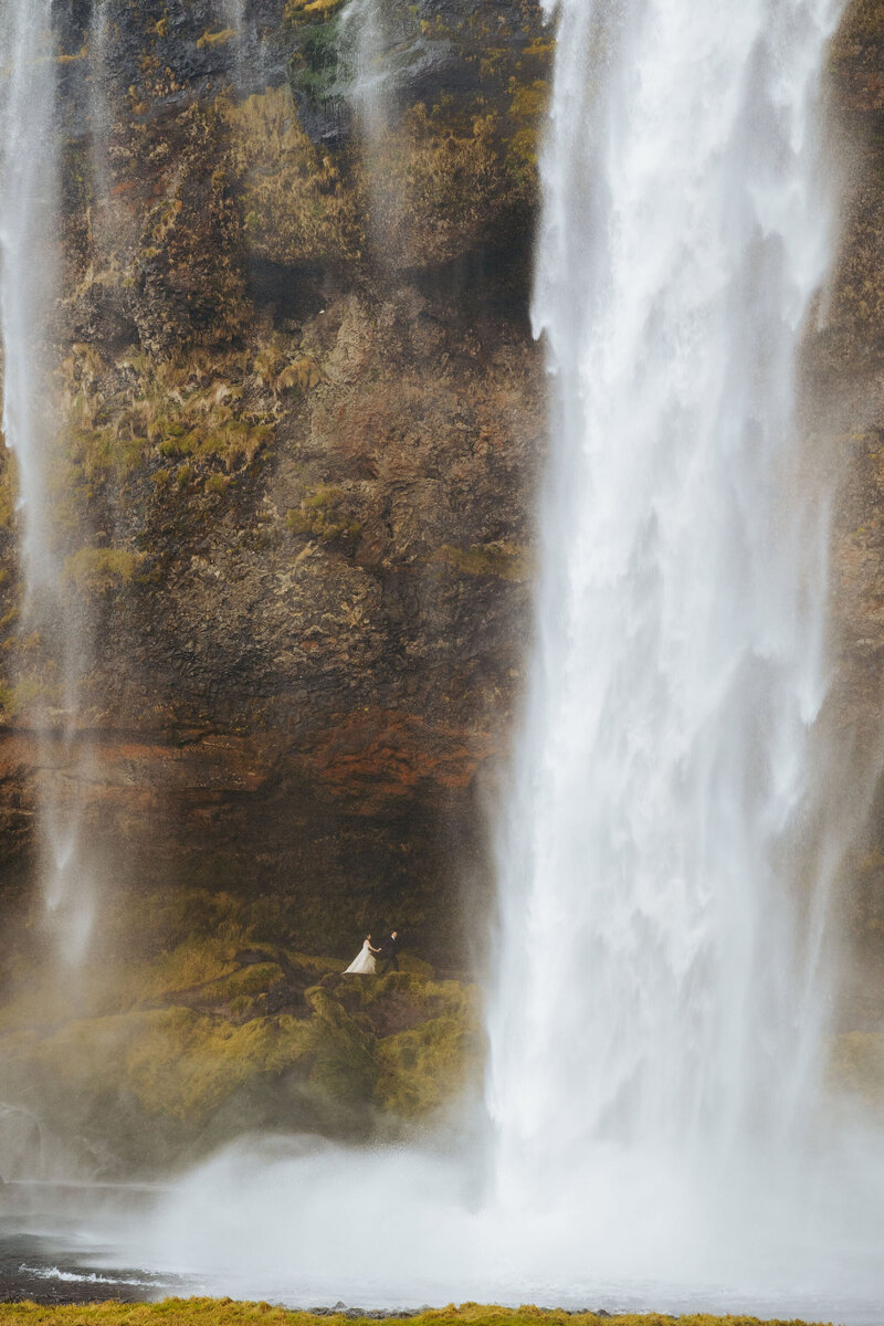 couple walking behind a waterfall in Iceland