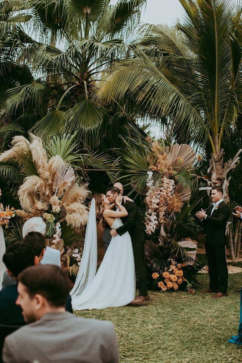 bride and groom kissing with palm trees