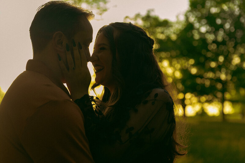 Newly married couple shares their first kiss in front of a rustic gazebo and the sun shines down on them
