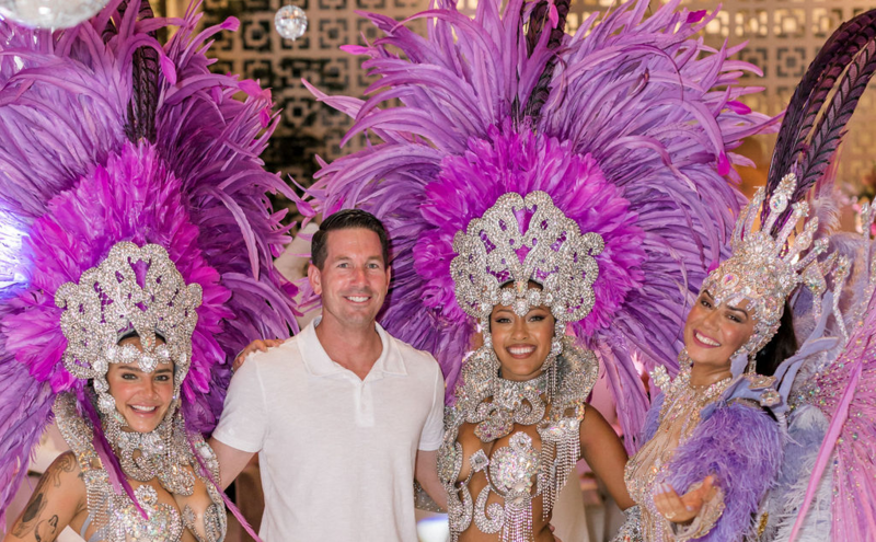 A man, surrounded by dancers dressed in Brazilian Carnival regalia,  celebrates his birthday at Hart and Main 