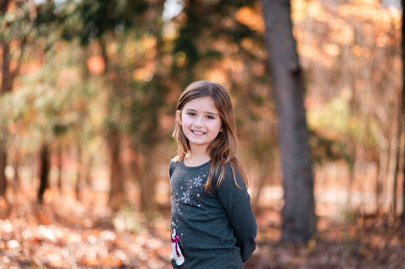 A young girl with long hair and glasses, wearing a leopard print cardigan and jeans, leaning back and smiling - Bloom by bel monili