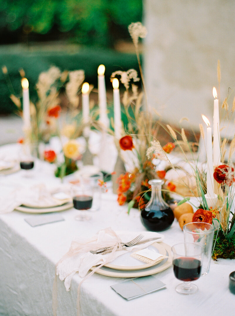 Farmhouse table with foraged flower arrangements, charcuterie and wine overflowing for a cozy fall wedding dinner