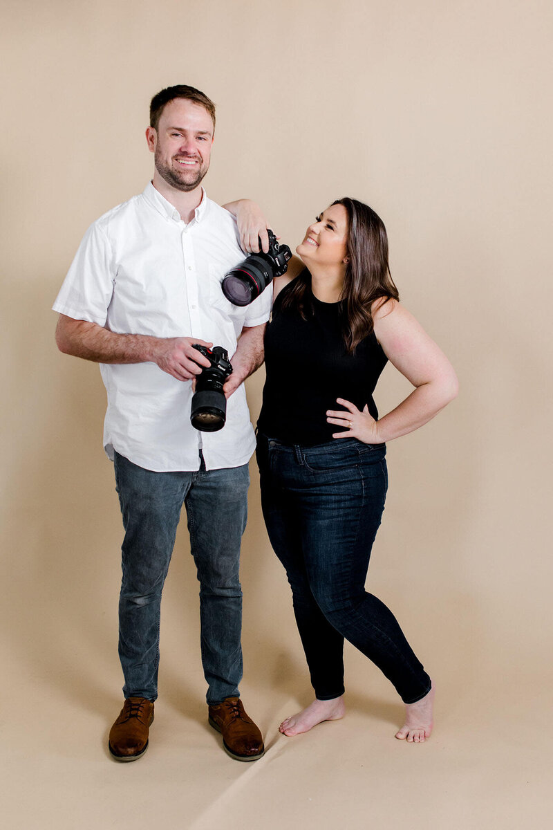 Photographer Michelle Franzetti and Videographer Nick posing with their cameras ready to film your perfect day.