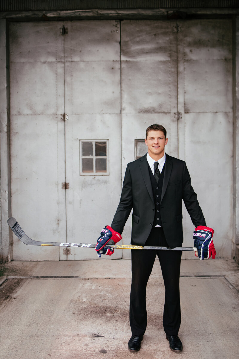boy in suit with hockey stick and hockey gloves